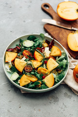 Fresh salad with fruits and greens on white wooden background close up. Healthy food.