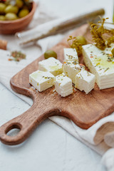 Fresh Greek Feta Cheese with olives. Healthy ingredient for cooking salad. Chopped Goat feta cheese on cutting board.