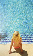 Children blond girl in swimming pool. Summer vacations.