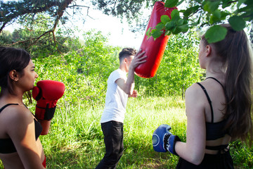 girls fighting boxing outside with coach in green park, sport summer people concept