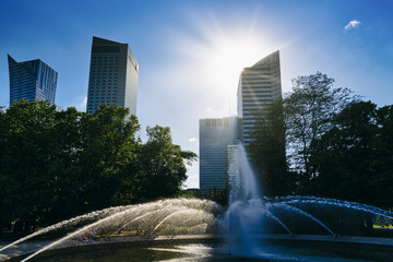 Warsaw City Center with office Skyscrapers Buildings and Fountain against Sun on Blue sky background at summer day in Poland