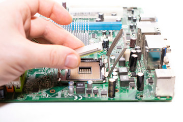 Engineer carefully installs a microprocessor CPU in the slot of the motherboard.