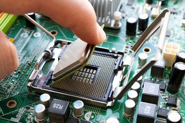 Engineer carefully installs a microprocessor CPU in the slot of the motherboard.