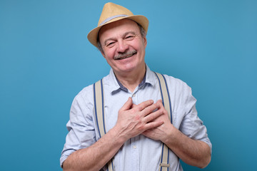 senior man posing in studio smiling joyfully, being pleased with compliment