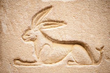 Ancient Egyptian hieroglyph of a hare carved in relief into a sandstone wall 
