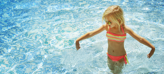 Children blond girl in swimming pool. Summer vacations.