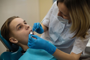 Dentist doing teeth checkup of guy in stomatology clinic.