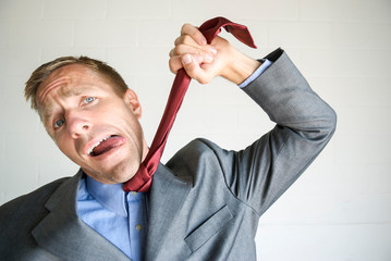 Businessman standing holding his tie like a hanging noose with a funny expression