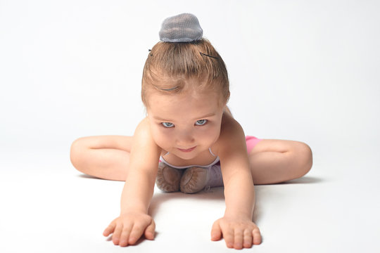 A little girl with a good stretch in a butterfly pose does yoga, horizontal photo on a white background.