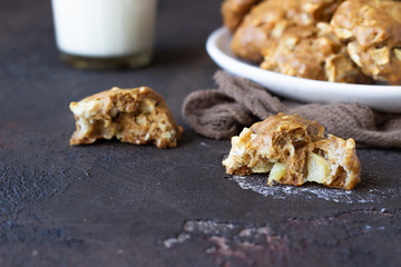 Homemade soft apple cookies on a plate with milk, dark concrete background. Dessert or breakfast for children, sweet snack. Selective focus.