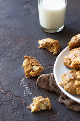 Homemade soft apple cookies on a plate with milk, dark concrete background. Dessert or breakfast for children, sweet snack. Selective focus.