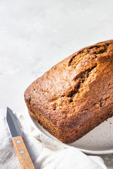 Sugar-free banana bread on a ceramic plate, light concrete background. Morning atmospheric lighting, trendy soft shadows, selective focus. Copy space. 