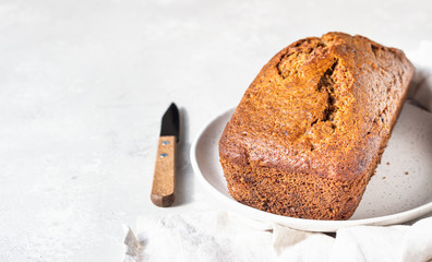 Sugar-free banana bread on a ceramic plate, light concrete background. Morning atmospheric lighting, trendy soft shadows, selective focus. Copy space. 