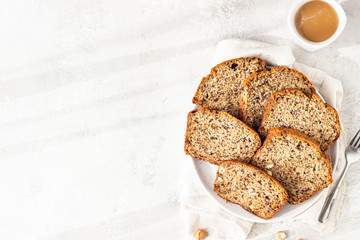 Sliced banana hazelnut bread on a ceramic plate with a cup of coffee. Morning atmospheric lighting,...