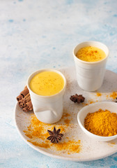 Turmeric golden milk or latte with curcuma powder, cinnamon and anise. Traditional Indian drink. Healthy ayurvedic drink. Light blue concrete background.