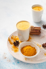 Turmeric golden milk or latte with curcuma powder, cinnamon and anise. Traditional Indian drink. Healthy ayurvedic drink. Light blue concrete background.
