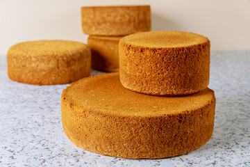 Prepare wedding cake from different sizes sponge cakes on table.