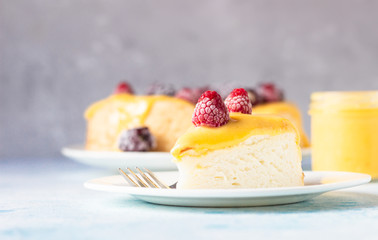 Slice of angel food cake with lemon curd and frozen berries (raspberry and blackberry), blue concrete background. 