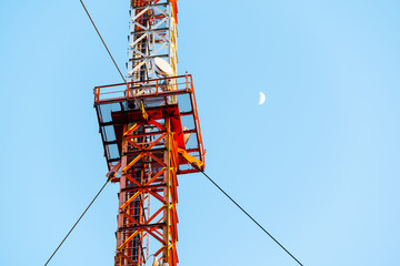 Funkmast mit Mond im Hintergrund, blauer Himmel, Closeup