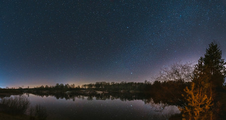 Belarus, Eastern Europe. Night Sky Stars Above Countryside Landscape With River. Natural Starry Sky Above Lake Pond In Early Spring Night. Russian Nature