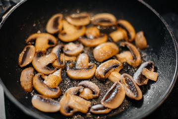 Thinly sliced fresh raw mushrooms are fried in a pan close-up. Healthy diet