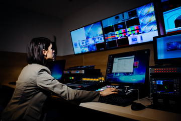 Female TV director control editing room in television studio.Operating vision mixer console...