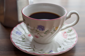 Coffee cup with a saucer and an italian coffee maker close up