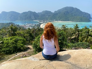 Fototapeta na wymiar woman sitting on top of mountain with a view on Phi Phi island