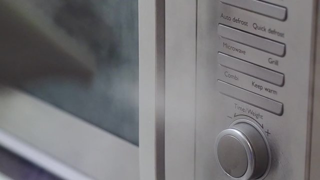 Using a steam cleaner to sterilise and kill bacteria and germs on a microwave oven door handle. Then wipe down with a cloth.