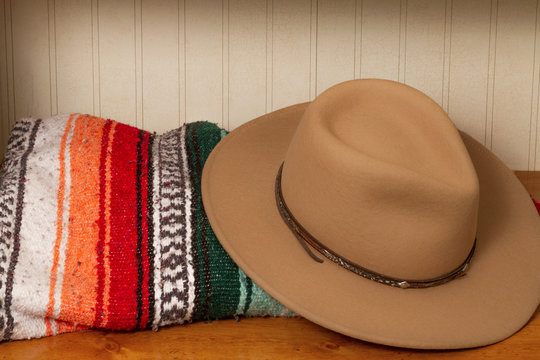 Brown cowboy hat with colorful Mexican blanket on a wooden table