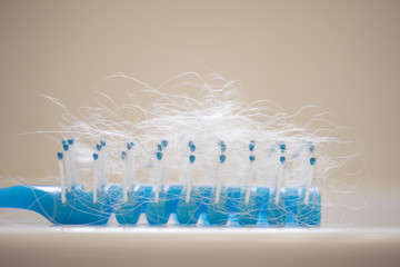 A lot of matted blond hair in a blue comb, side view on a bathroom shelf.