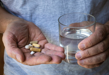male hands holding pills and grass of water