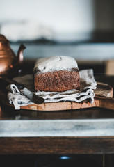 Healthy rye Swedish bread loaf cut in slices covered with flour with vintage knife on wooden board over kitchen counter, selective focus