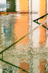 Weathered mooring line with algae on a blurred building distorted reflection in the water surface...