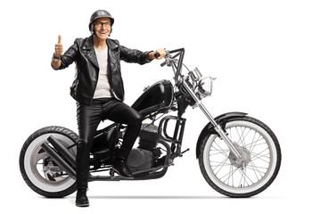 Obraz na płótnie Canvas Cool senior biker sitting on a chopper motorbike and showing thumbs up