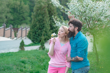 Happy couple smiling in a spring park on a sunny day. Romantic date couple concept. Portrait of young couple smiling on spring blossom background.