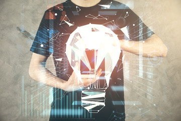 Double exposure of man's hands holding and using a digital device and bulb hologram drawing. Idea concept.