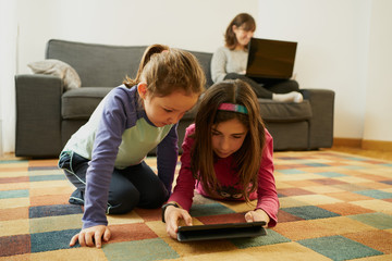 two girls play in the living room while their mother teleworks