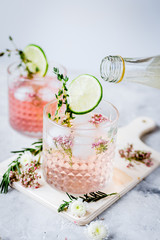 making cocktails in glasses with lime and herbs on stone kitchen desk background