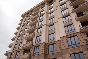 the facade of the multi-storey building is brown in color with black frame windows and architectural elements of molding and rusting, close up.