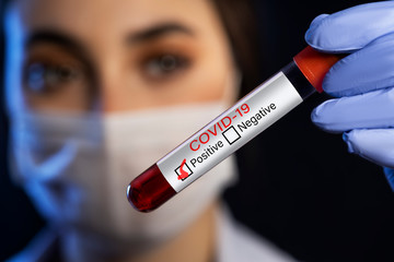 Fototapeta premium Woman doctor holding a blood test which is signed as covid-19 positive.
