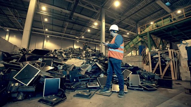 Male engineer is observing a landfill unit filled with rubbish