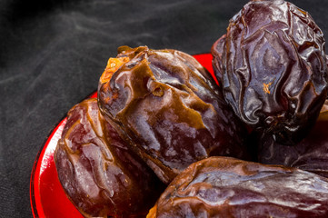 Big luxury dried date fruit in bowls on the dark surface, kurma ramadan kareem concept, close up.