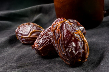 Big luxury dried date fruit in bowls on the dark surface, kurma ramadan kareem concept, close up.