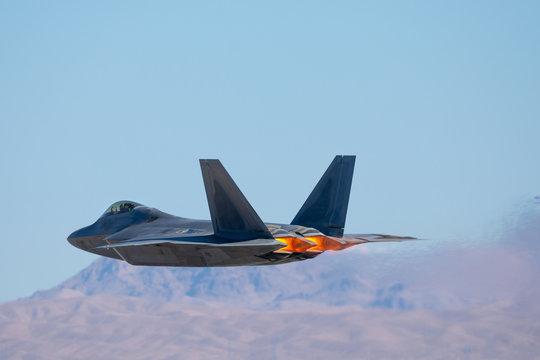 Very low pass of a F-22 Raptor against the Nevada hills, with afterburners on and  
the jet stream visible behind the aircraft
