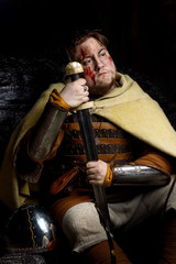 A Scandinavian warrior viking wounded in leather and metal armor with a fighting sword and helmet...