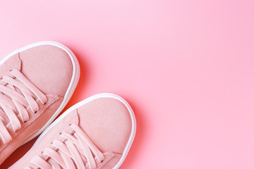 Female pink sneakers on a pink background close-up, top view, copy space
