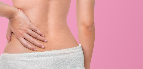 Back view of woman touching the hip or waist wear towel isolate on pink background, Clipping path, Back ache and beauty concept.