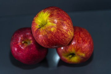 Fruits of macã (Malus domestica) in natura on dark and mirrored background
