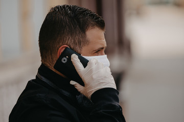 White bearded adult man using smartphone while wearing surgical mask.